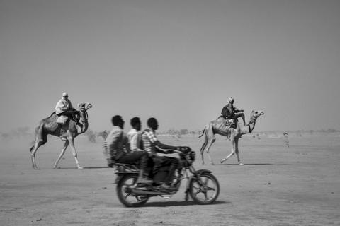 Hier hat Ferhat Bouda auf den Auslöser gedrückt, als zwei Männer auf Kamelen reiten, während im Vordergrund ein Motorrad mit drei Männern vorbeisaust. Foto: Fotografie Forum Frankfurt