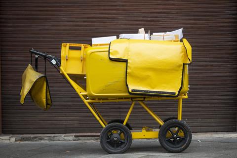 Ein Briefträgerwagen der Deutschen Post für die Hausbelieferung steht auf einer Straße. 