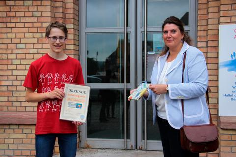 Erdkundelehrerin Juliane Jurkat überreicht Schulsieger Liam Schümmer neben der Urkunde ein kleines Reisetagebuch.  Foto: Hammerschmied 