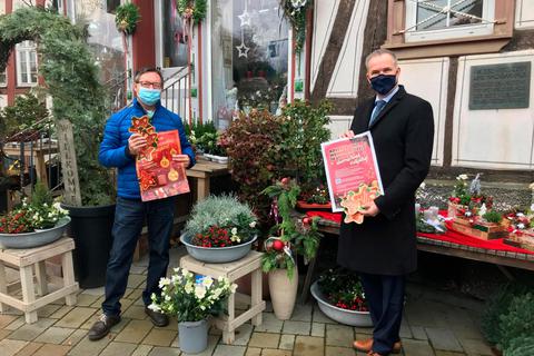 Bürgermeister Steffen Wernard (rechts) und Gewerbevereinsvorsitzender Ralf Müller (links) präsentieren die diesjährige "Advents- und Weihnachtszeit in Usingen" Foto: Stadt Usingen 