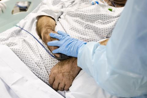 Eine Krankenschwester berührt die Hand eines am Coronavirus erkrankten Patienten. Foto: dpa