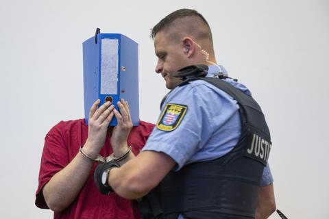 Der Angeklagte, der im Ayleen-Prozess in Gießen vor Gericht steht, verdeckt sein Gesicht mit einem Aktenordner.      