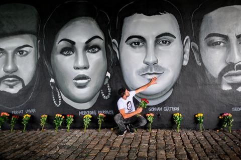 Çetin Gültekin, Bruder des Opfers Gökhan Gültekin, legt seine Hand auf das Porträt seines Bruders. Ein Gemälde unter der Frankfurter Friedensbrücke zeigt die Por-träts von neun Opfern der Anschläge in Hanau.   Archivfoto: dpa 