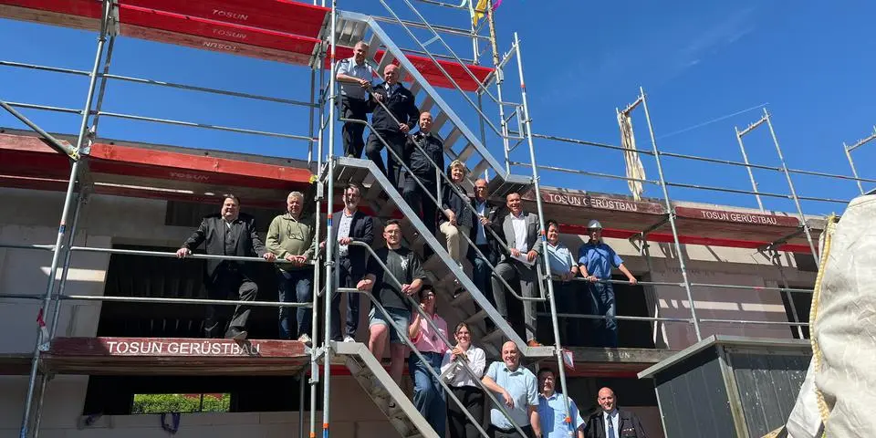 Auf der Erfolgsleiter zum Feuerwehrdienstleistungszentrum: Sie stehen beim Richtfest auf dem Rohbau des Werkstattgebäudes, einer von drei Komplexen in Bad Camberg: Bauherren, Bürgermeister der fünf Kommunen, Brandinspektoren, ehrenamtliche Feuerwehrleute und der Architekt.