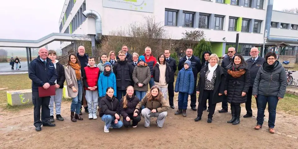 Teilnehmerinnen und Teilnehmer sowie Verantwortliche der Schul-AG "Mehr Feuerwehr an der Schule": Feuerwehrkameradinnen und Kameraden aus den Hünfeldener Ortsteilen mit Bürgermeisterin Silvia Scheu-Menzer (parteilos, Fünfte von rechts), Schulleiterin Judith Lehnert (Dritte von rechts), Gemeindebrandinspektor Kai Krebs (Siebter von rechts), Schul-AG-Verantwortliche Franziska Rittweger (Dritte von links) und der Teamleiter während der AG, Diethard Hofmann (links) vor der Freiherr-vom-Stein Schule in Dauborn. © Dieter Bäbler