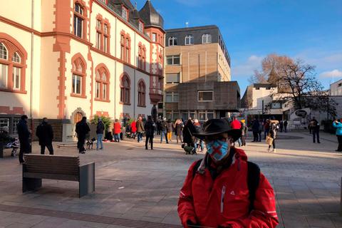 Ein Demonstrant verteilt Flugblätter in Limburg. Das rote Kreuz bedeute, dass er gegen die Corona-Maßnahmen sei, sagt er.  Foto: Mika Beuster 
