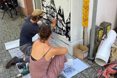 Die ehemals gelben Kästen in der Altstadt, hier Ecke Commerzbank am Kornmarkt, erhalten eine weniger auffällige Farbe, dafür sorgt ein Künstler mit einem Altstadtmotiv für ein attraktives Bild.