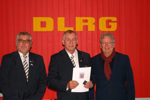 Den Ehrenbrief des Landes Hessen bekommt Jörg Ehlig (Mitte) im DLRG-Vereinsheim von Jörg Sauer (rechts), links: Jan Letanoczki.  Foto: Mike Holz 