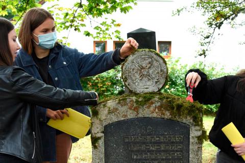Die Schülerinnen Aileen (v.l.), Anna und Diana reinigen den Grabstein von Mathilde Bravmann auf dem jüdischen Friedhof in Weilburg. Foto: Joachim Warlies 