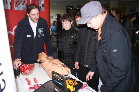 Joachim Scholz vom Jugendrotkreuz lädt die Schüler dazu ein, Wiederbelebungsmaßnahmen mit einem Defibrillator an einer Dummy-Puppe zu üben.