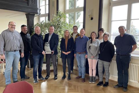 Staffelholzübergabe für den Jugendkirchentag 2024 in Biedenkopf: Jochen Achenbach (3.v.l.) nahm die steinerne Eule aus den Händen von Dekan Andreas Friedrich entgegen. Mit ihnen freuen sich (v.l.) Klaus Grübener, Jürgen Niess, Conny Habermehl, Elian Lorenz, Thomas Rößer, Jennifer Hallenberger, Jasmin Betz, Andrea Kirchner und Christian Reifert auf das Großereignis vom 30. Mai bis zum 2. Juni 2024.