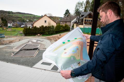 Bürgermeister Christoph Felkl zeigt den Plan für das neue Kinderbecken im Niederdietener Freibad. Die Arbeiten sollen im Juni abgeschlossen sein. Das auf zwei Stufen angelegte Becken ist schon erkennbar.  Foto: Mark Adel 