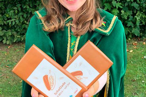 Sophia Krämer absolviert ihren ersten Termin als Kirschenkönigin 2021 bei der Feier "10 Jahre Fairtrade-Stadt" in Gladenbach und freut sich über die fair gehandelte Schokolade.  Foto: Uta Neumann 