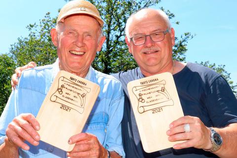 Die schmucken Holzbrettchen für das Kirschenmarkt-Frühstück des Männergesangverein Gladenbach sind fertig: Karl Reinhardt und Uwe Stöfhas haben das Logo und den Schriftzug "Trotz Corona" eingebrannt.  Foto: Michael Tietz 
