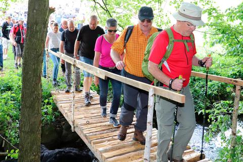 Trockenen Fußes überqueren die Weidenhäuser Grenzgänger den Römershäuser Bach - dank der von zwei Feuerwehrleuten gezimmerten Brücke, die dann für einen guten Zweck versteigert wurde.  Foto: Michael Tietz 