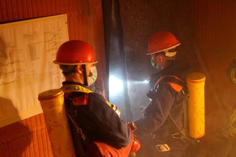Mit Atemschutzgeräte-Attrappen ausgestattet, durchsucht ein sogenannter Angriffstrupp den Rohbau eines Mehrfamilienhauses nach möglichen Brandherden. Foto: Patrick Stein 