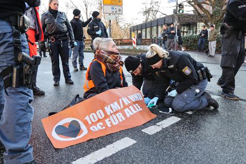 Polizisten lösen die an die Straße festgeklebte Hand einer Klimaaktivistin. Am Morgen hatten sich Klimaaktivisten in Marburg auf eine Straße gesetzt und sich festgeklebt. 