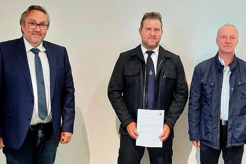 Breitscheids Bürgermeister Roland Lay (l.) und der Vorsitzende der Gemeindevertretung, Arnd Kurek (r.) überreichen dem wiedergewählten Medenbacher Wehrführer Sascha Bott die Ernennungsurkunde für die nächsten sechs Jahre.  Foto: Christoph Weber 