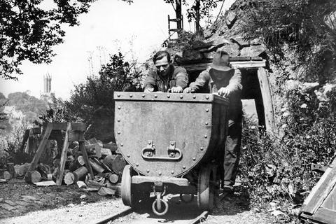 Dieses historische Bild zeigt zwei Bergmänner der Grube Laufenderstein in Dillenburg mit einer Lore um das Jahr 1940, im Hintergrund der Wilhelmsturm.  Foto: Sammlung Rolf Georg 