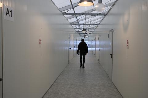 Tobias Bell, der Leiter der Flüchtlingsunterkunft in Haiger, geht durch eines der beiden Wohnzelte, vorbei an den Türen der kleinen Zimmer. Insgesamt 193 Menschen leben aktuell in der Unterkunft.
