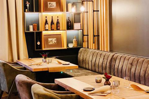 Im Restaurant „Culinarik“ sind die Wände mit hellem Holz verkleidet, das Licht ist warm, die Stühle sind gepolstert und im Hintergrund stehen Weinflaschen in einem Regal.