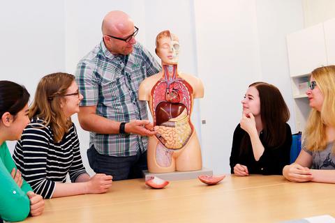 Michael Schäfer, Lehrer für Pflegeberufe an der Krankenpflegeschule der Lahn-Dill-Kliniken, erklärt einigen seiner Schülerinnen anhand eines Modells den Aufbau des menschlichen Körpers.  Foto: Lahn-Dill-Kliniken 