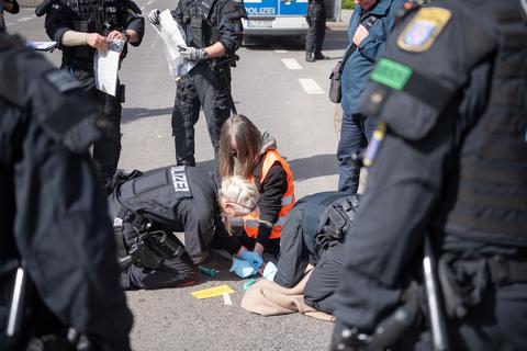 Polizeibeamte lösen während eines Protests der Gruppe „Letzte Generation“ die Hand eines Demonstranten. Dieser hatte sich mit Sekundenkleber auf der Fahrbahn festgeklebt.             Archivfoto: dpa