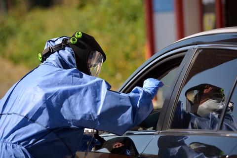 Einem Reisenden wird direkt im Auto eine Probe genommen, die auf das Coronavirus untersucht wird. Foto: dpa