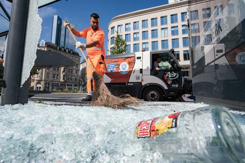 Mitarbeiter der Stadtreinigung beseitigen am Morgen vor der Alten Oper Scherben der zertrümmerten Scheiben einer Bushaltestelle. Foto: dpa
