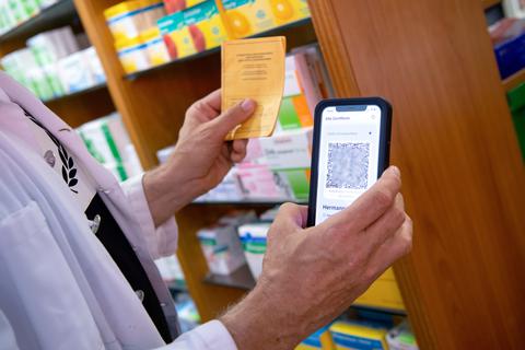 Ein Apotheker hält einen Impfpass und einen digitalen Impfnachweis in den Händen. Ein Teil der Apotheker startet mit dem Ausstellen des neuen digitalen Nachweises einer Corona-Impfung. Dabei wird für vollständig Geimpfte ein QR-Code erstellt, der in Apps mit dem Handy verwendet werden kann. Foto: dpa