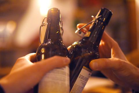 Zwei Männer stoßen mit Bierflaschen an. Private Treffen in geschlossenen Räumen erwiesen sich laut Mainzer Forscher als Hauptansteckungsherd während der Pandemie. Archivfoto:  Jan Woitas/dpa