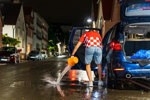 Ein Mann schöpft am Mittwoch im rheinland-pfälzischen Bodenheim Wasser aus seinem Auto ab. 