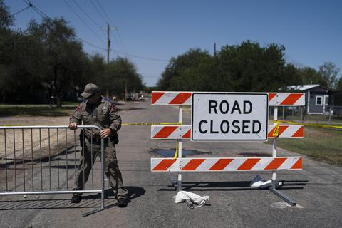 Ein Polizist baut eine Straßenabsperrung vor der Robb Elementary School auf. Ein 18-jähriger hat bei einem Amoklauf in einer Grundschule im US-Bundesstaat Texas mehrere Menschen getötet.  Foto: dpa