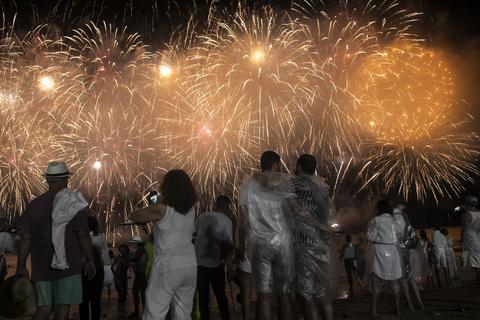 Brasilien, Rio De Janeiro: Menschen blicken bei den Silvesterfeierlichkeiten in den Nachthimmel, während ein Feuerwerk über dem Copacabana-Strand explodiert. Foto: dpa