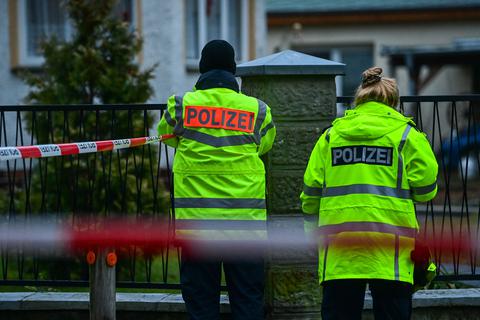 Polizisten steht in einem Wohngebiet von Senzig, einem Ortsteil der Stadt Königs Wusterhausen im Landkreis Dahme-Spreewald, hinter einer Absperrung. Die Polizei hat dort fünf Tote in einem Wohnhaus gefunden.  Foto: dpa