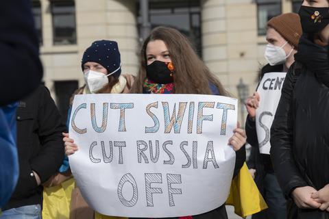 Teilnehmer an einer Solidaritäts-Demonstration für die Ukraine stehen auf dem Pariser Platz mit einem Plakat "Cut Swift Cut Russia Off". Foto: dpa