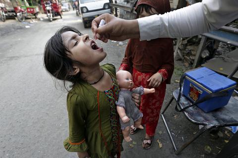 Eine Mitarbeiterin des pakistanischen Gesundheitswesens verabreicht einem jungen Mädchen im Rahmen einer Polio-Imfpkampagne eine Schluckimpfung. Archivfoto: dpa
