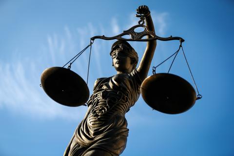 Eine Statue der Justitia hält eine Waage in der Hand.