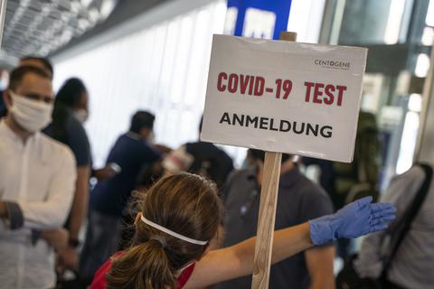 Eine Bedienstete weist in einem Terminal des Frankfurter Flughafens den Weg zur Anmeldung für einen Corona-Test.  Foto: Frank Rumpenhorst/dpa