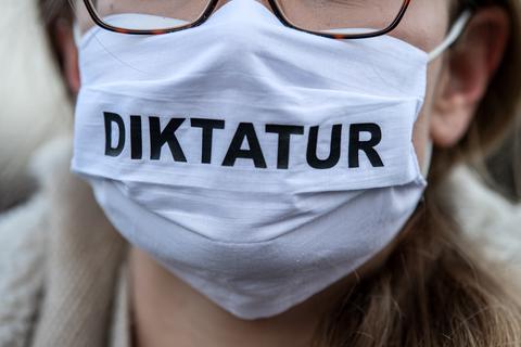 Eine sogenannte Querdenkerin trägt auf einer Demonstration einen Mundschutz mit der Aufschrift "Diktatur". Foto: dpa