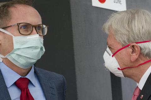 Mit Maske unterhalten sich Ministerpräsident Bouffier und Gesundheitsminister Klose. Foto: dpa