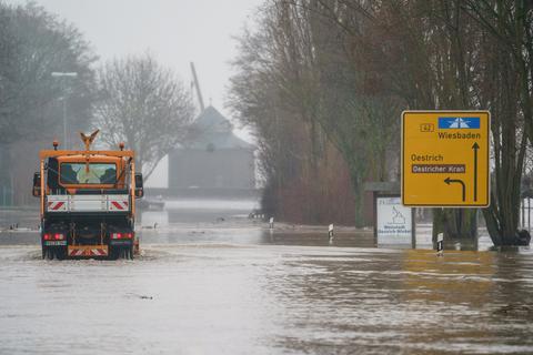 Ein städtisches Fahrzeug befährt die überschwemmte und gesperrte B42 bei Oestrich-Winkel im Rheingau. Ergiebige Regenfälle lassen die Pegelstände der Flüsse in Hessen weiter steigen. Foto: dpa/Andreas Arnold