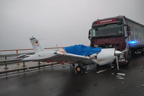 Ein beschädigtes Flugzeug steht auf der Autobahn 62 vor einem LKW. Ein Flugzeugpilot hat eine Brücke der Autobahn 62 als Notlandepiste genutzt.  Foto: Polizeidirektion Pirmasens/dpa 