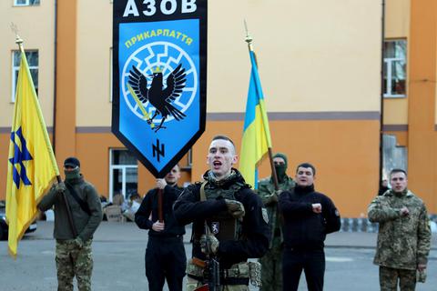 Mitglieder des Asow-Regiments schwören bei einer Zeremonie Ende März in Iwano-Frankiwsk dem ukrainischen Volk ihre Treue. Auf der Fahne erkennt man rechtsextreme Symbole wie die „Schwarze Sonne“ und die Wolfsangel-Rune. Foto: dpa