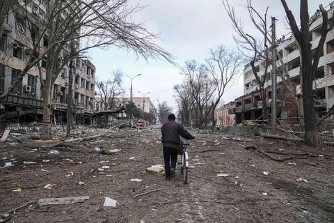 Ein Mann bahnt sich mit einem Fahrrad den Weg durch die von Zerstörung geprägten Straßen der Hafenstadt Mariupol. Foto: dpa 