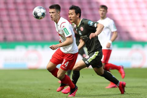 Kölns Noah Katterbach (l.) und der Mainzer Dong-won Ji kämpfen um den Ball. Foto: Lars Baron/Getty/Pool/dpa