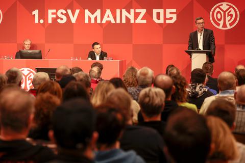 Vorsitzender Stefan Hofmann (am Podium) spricht auf der Mitgliederversammlung des 1. FSV Mainz 05. Christian Heidel sitzt links neben ihm und hört zu.