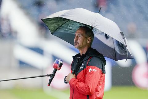 Frankfurts Trainer Adi Hütter kommt mit Regenschirm ins Stadion. Foto: dpa