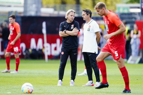 Kaiserslauterns Trainer Dirk Schuster (rechts) und Kaiserslauterns Co-Trainer Sascha Franz stehen beim Aufwärmtraining auf dem Spielfeld.