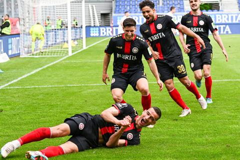 Die SVWW-Befreiung gegen den SC Verl: Stürmer Ivan Prtajin (am Boden) lässt sich nach seinem 2:1-Siegtreffer, der im Aufstiegskampf extrem wichtig ist, von seinen Mannschaftskollegen feiern. 